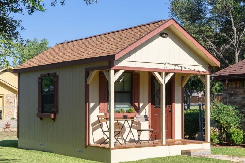 The exterior of a painted storage shed with a small porch.